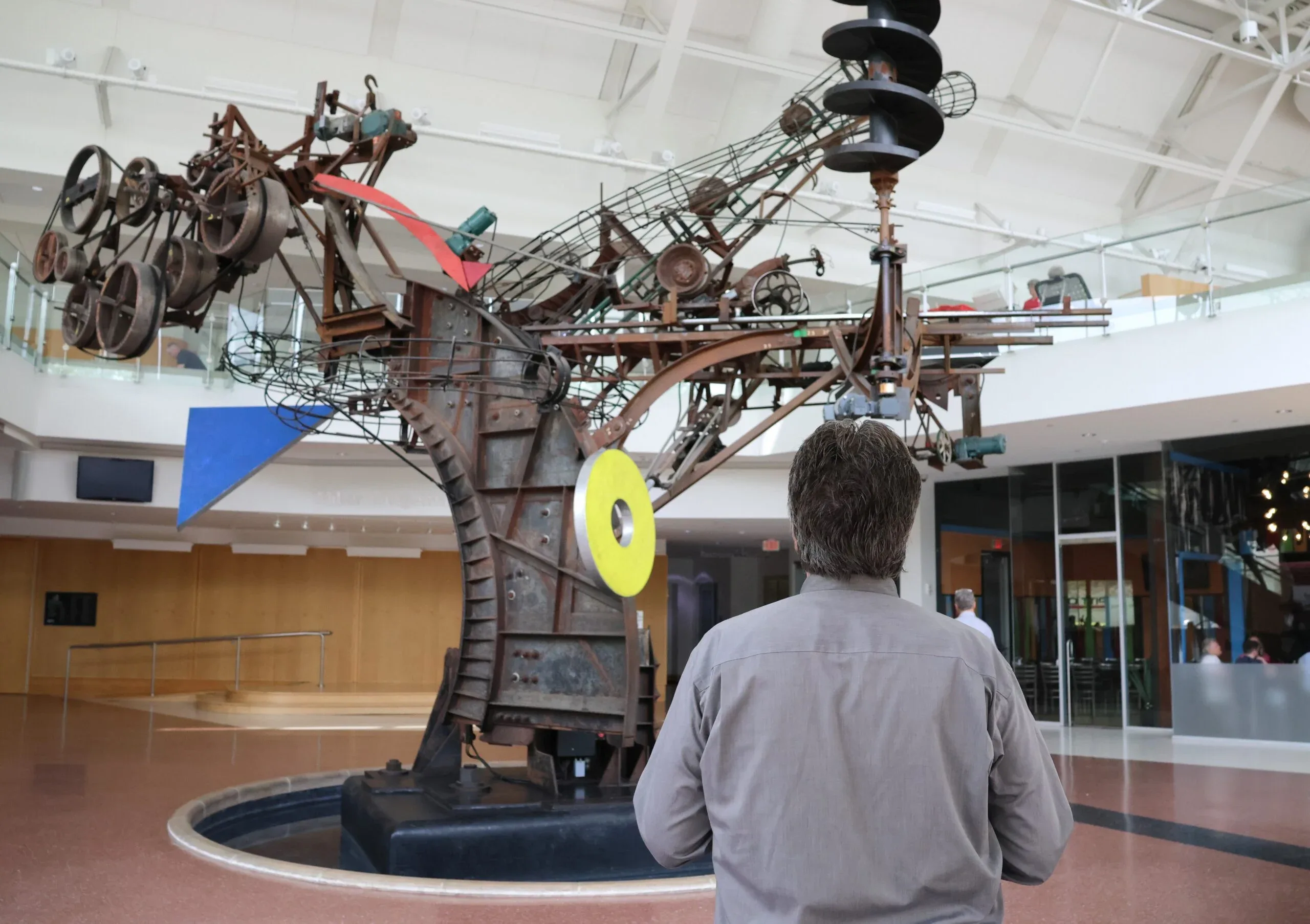 Kinetic sculpture "Chaos I" by Jean Tinguely at The Commons in Columbus, IN with a man looking at it and taking photos.